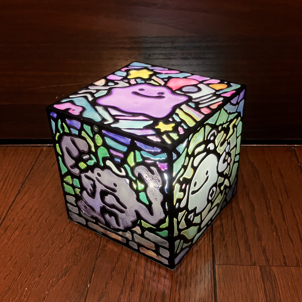 ukigumo413's tweet photo. 地域クラブ活動でやったボンドステンドグラスの技法で、うちの子と置き型のライト作ったよ☺️

百均のキューブボックスの5面に、メタモンと見た目が完全に変わるへんしん4種類。
主線は母ちゃん、着色は娘。
キャラ部分は半透明・背景部分は透明寄りで塗り分けてメリハリつけました。

#みょこさん工作 https://t.co/4KY0zbqKwE
