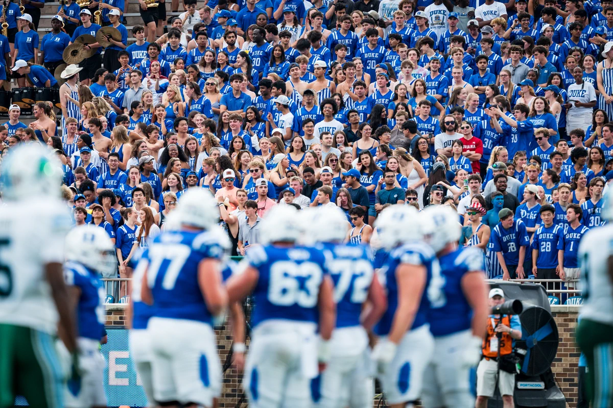Duke football huddle with crowd in background. 