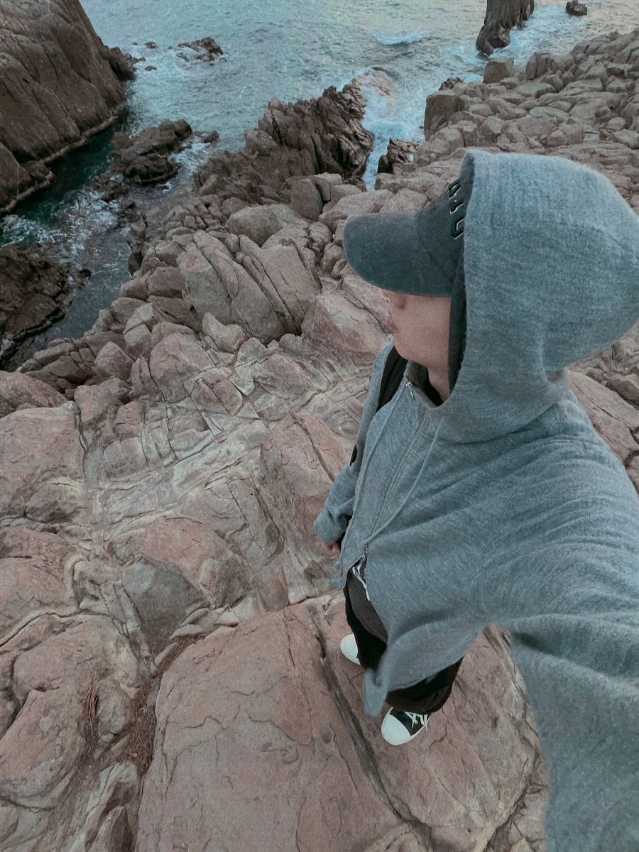 jigng's tweet photo. Salt air, rugged stone, and an overcast horizon set the scene for a solitary escape. Hood drawn close and cap pulled low, I keep my gaze toward the waves, blending into the muted landscape like I was meant to disappear into the coast. https://t.co/YqYetvfMat