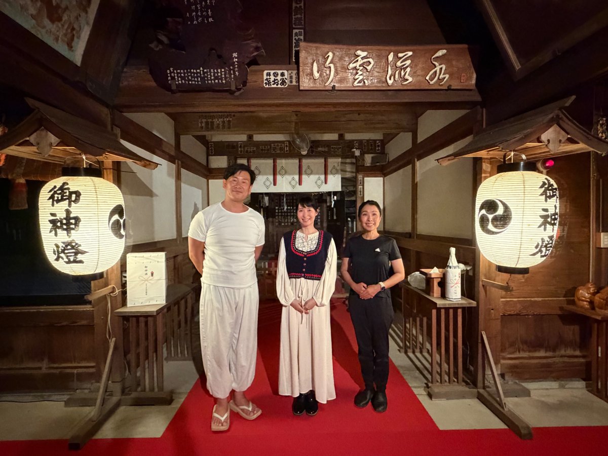 raidenjinja's tweet photo. 千年の森が、夜に表情を変えます。

日が落ちると、上之雷電神社の境内にそっと灯りが入ります。熊谷市最古と伝わる石鳥居が闇の中に浮かび上がり、幾百年もの祈りを刻んだ森の木々が、夜気の中で静かに息をしています。電気を司る大雷神（おおいかづちのかみ）の社らしい、光の演出です。

その森の中で写真展が開かれています。氏子区域のご出身で、俳優・写真家として活躍される花澄さんの作品が、吊り下げられた灯りに照らされ、木立のあいだに並んでいます。イタリアの写真展で金賞を受けた方が、この森を選んでくださいました。

昨夜、花澄さんが森の様子を見にご来社くださいました。千年の鎮守の森と人の営みが、こうして静かに交わっています。

夜の参道に足を向けると、そこには昼とはまったく異なる社の姿があります。

#上之雷電神社 #熊谷神社