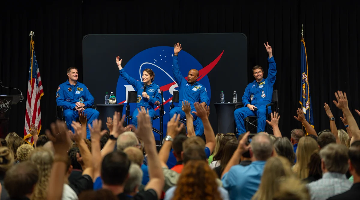 The crew of NASA’s Artemis II mission – NASA astronauts Reid Wiseman, Victor Glover, and Christina Koch, and CSA (Canadian Space Agency) astronaut Jeremy Hansen – visited Huntsville, Alabama, Tuesday, Aug. 1, where they met with the NASA workforce at NASA’s Marshall Space Flight Center. In this image, the crew sit on stage with their hands raised facing a crowd of NASA Marshall eployees who also have their hands raised. Credit: NASA/Brandon Hancock