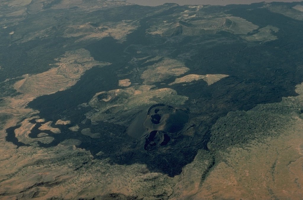 vulcaniya's tweet photo. The Barrier, Turkana County, Kenya, 7 September 2026

In 1888 Sámuel Teleki and Ludwig von Höhnel came down the eastern shore of the lake they had just named for the Austrian crown prince and found a cone in eruption at the southern end of it. A. M. Champion, who wrote the area up for the Geographical Journal in 1935, recorded that the lava had run several miles to the shoreline and that the party had to work round the southern side of the flow to get past. The cone kept Teleki's name. It stands 646 metres above sea level on the northern flank of The Barrier, the volcanic complex that fills the floor of the East African Rift at the southern end of Lake Turkana, and it is among the youngest features on a mountain whose caldera collapsed roughly 92,000 years ago.

The name describes a function rather than a shape. The complex occupies the rift from wall to wall, with Lake Turkana on its northern side and the Suguta Trough, the site of a former lake, on its southern one. It is not a single volcano. Four shield volcanoes overlap here: Kalolenyang to the west, Likaiu West and Likaiu East to the east-north-east, and Kakorinya, the youngest, sitting directly over the rift axis. The crust beneath is being stretched and broken, and magma has risen along whatever fractures were open rather than through one lasting conduit, which is why the complex spreads across the rift floor as lava fields, fissures and cones instead of rising to a single summit.

Kakorinya's summit gave way about 92,000 years ago, leaving a caldera 3.8 kilometres across. The eruption responsible is poorly documented compared with the collapse itself, but what followed is plain enough in the rock. Trachytic and phonolitic magma came back up inside the depression and along its ring fracture, building stiff domes and short, thick flows that now cover much of the caldera floor. The hole did not stay open for long.

Later activity moved outwards and changed character. Fissures across the northern and southern flanks fed basalt, fluid enough to spread in sheets, and built lines of scoria cones from the early Holocene onwards. Some of that lava is young by any reasonable measure. Three separate flows on the northern flank have been dated by their magnetism to somewhere around a thousand years old. The contrast is one of the more legible things about the volcano: viscous, evolved lava inside the old caldera, and basalt running out across the rift floor around it.

Where those flows reach the lake, magma has had to contend with water. Nabuyatom, at the northern edge of the complex, is a tuff cone rising about 180 metres above Turkana, steep-sided and flat-topped, built when rising magma met lake water and fragmented instead of flowing. Its lower slopes carry none of the terraces cut by earlier, higher stands of the lake, which is one reason its age has never been settled. The shoreline here has advanced and retreated repeatedly, and the volcano has grown through it.

Cavendish and Andrew, working up the Suguta in the same decade as Teleki, found the water at the northern end of Lake Logipi hot enough to wash in and a smouldering cone standing above it, which Cavendish named after his companion. Andrew's Cone and Teleki's Cone between them account for the whole recorded eruptive history of The Barrier: explosions and lava around 1871, then 1888, 1895 and 1897, an episode in 1917 credited to one cone or the other, and a last confirmed eruption of explosions and lava at Teleki's dated to about 1921. The entry for 1897 includes evacuations alongside the explosions and the flames.

Reports reaching Europe a few years after Teleki passed had it that his volcano was gone, that the lake had overflowed, water had reached the crater and a single explosion had left a flat plain of lava where the cone once stood. The cone is still there. Distance and second-hand telling did most of the work in that account, and it took Champion's own expedition in the 1930s before anyone mapped the ground closely enough to say so.

Heat has outlasted the eruptions. Solfataras vent inside Kakorinya's caldera and on the western and southern flanks, altering the ground where the gas escapes, and the Suguta side still carries hot springs and a geyser near Lake Logipi.

Vulcaniya | Volcanoes • People • Planet