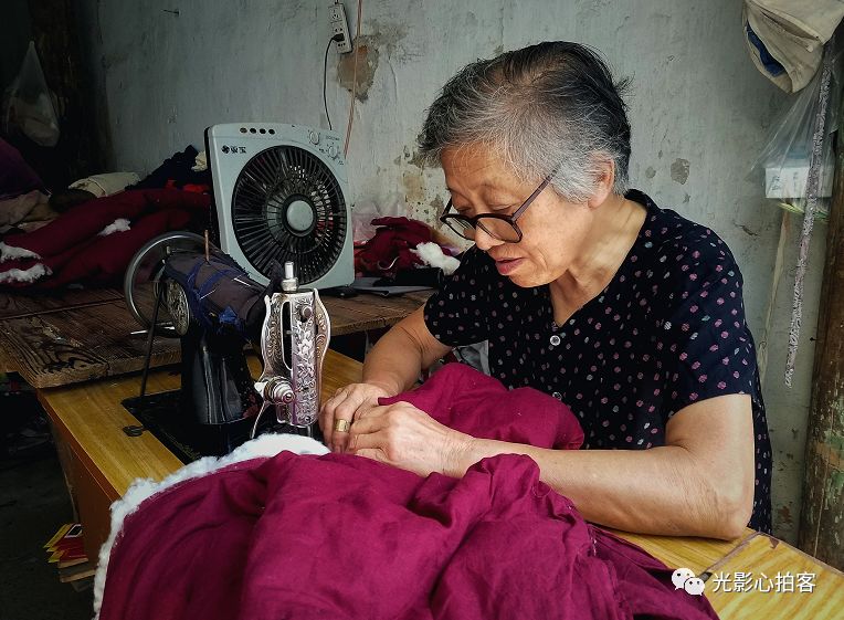 aryurbaez's tweet photo. Just happened to pass by a narrow alley, and caught this sweet old grandma sitting under the awning, mending her grandson’s school uniform — the sunlight filtering through the window made the whole scene feel so warm and quiet. // https://t.co/ruOA26hB2o