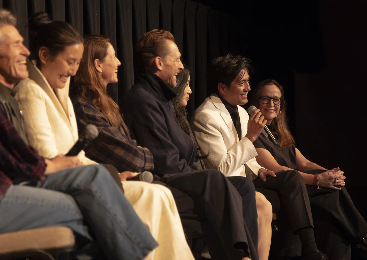 From the world premiere of Tenzing. Various castmates and crew members sit on a panel together, smiling. Genden Phuntsok holds a microphone and speaks.