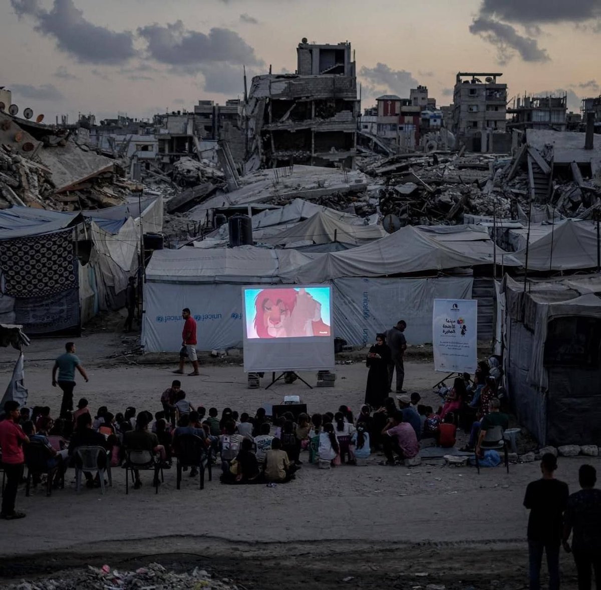 festivalesgt's tweet photo. ¡No dejemos de hablar de Palestina! 🇵🇸 En medio del aire libre y el atardecer, un grupo de niños palestinos se reunió el 30 de agosto para ver El Rey León (1994). Alrededor de ellos no hay salas de cine, sino escombros y estructuras devastadas por el conflicto.

📷 Fotografías: Omar Ashtawy