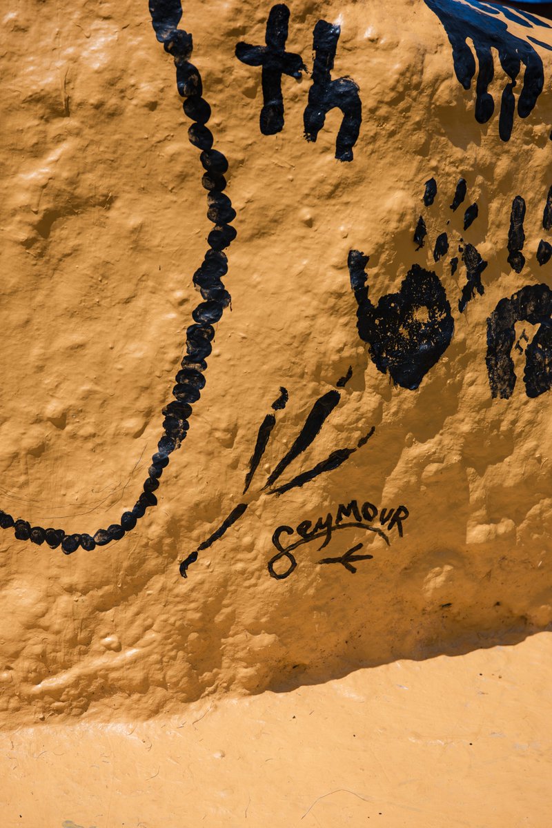 A gold painted rock covered in black paint featuring handprints and a talon featuring Seymour's signature.