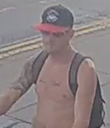 A shirtless man wearing a dark baseball cap with a red brim and a backpack, captured in a low-resolution CCTV image.