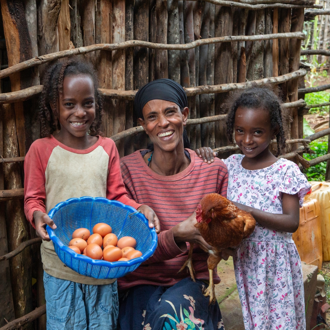 Mihret poses with her daughters, Tsega, 11, left, and Eden, 7, right, alongside eggs collected from the family’s chickens. Photo by Heifer International/Russell Powell.