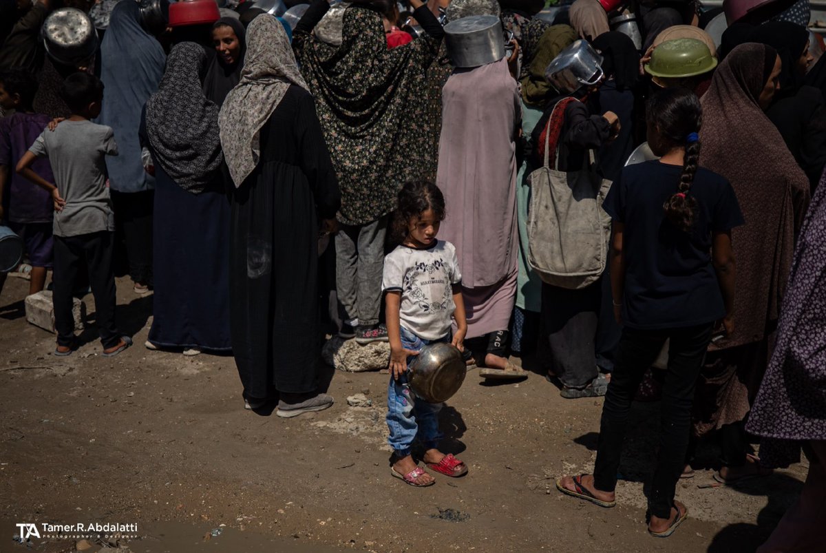 EyeonPalestine's tweet photo. Lines heavier than childhood itself.. A little girl stands quietly amidst the crowd, holding her pot while waiting for her turn to get her family's meal. https://t.co/wDzLGnmW8O