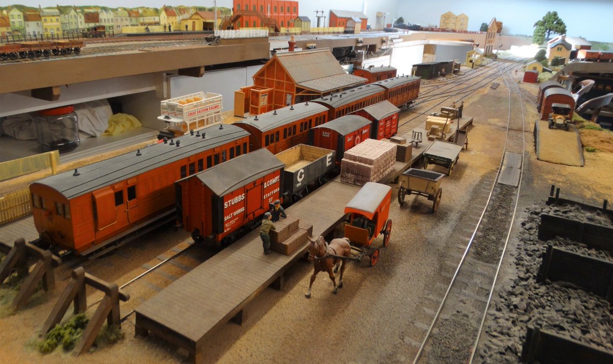 GERrailsoc's tweet photo. It’s not playing with trains, well, not always, it’s railway modelling. 

Railway modelling in the UK is not a dusty relic of bygone times. It is a living craft with a complex history, Hornby, Bachmann, Peco, countless clubs, large and small and many exhibition halls full of people who are new to the hobby and those who have spent decades building a miniature Britain. It also happens to be one of the most complete hobbies you can start: engineering, art, history, electronics, geology, architecture, community and quiet focus, all in one box.

Hornby commissioned a UK survey of 2,000 adults, which revealed more than 60% of scale-modellers reported mental-health benefits. Nearly half specifically cited stress relief and improved mental activity. Among people who actually make models rather than just run trains, that figure rose to around 80%.
The reasons are practical, not mystical: You build a world you control, the trains run on time, but only if you want them to, the weather is whatever you paint.  The work is tactile and sequential, laying track, ballasting, constructing buildings, wiring points, creating scenery, weathering a wagon; each and every task demands attention without serious consequences when you get it wrong, which even the most experienced modeller does. The hobby maps almost perfectly onto the NHS “five ways to wellbeing”: connect (clubs and shows), keep learning, give (help a newcomer, run a layout at an exhibition), take notice (the meditative act of watching a train crawl through scenery you made), and a modest amount of physical activity.
Modelling scales with your energy. Some days you only run trains. On other days, you may rebuild a cutting or perhaps plant some trees.

People describe model railways as meditation with ballast. That is not marketing copy; it is a recurring phrase in first-person accounts.
The costs: from modest to magnificent. You do not need a spare bedroom and a second mortgage to get started. Models can be built on a shelf, in a bookcase, on a board under the bed, right through to taking over a whole garage, using a shed or venturing out into the garden.

There are various gauges, but by far the most common in the UK is OO, which is the British version of the American HO. The track is the same width, but the model scale dimensions are different.

With a starter layout, expect to pay between £50 and £200. For that, you'll get an oval, maybe with a siding or passing loop with a Hornby or similar starter set: loco, coaches/wagons and controller.

For a small finished layout, expect to spend £250–£600, with extra stock, basic scenery, a 4×2 ft board that actually looks like a place you'd recognise.

For a serious enthusiast, it's open-ended, a layout is never finished, there are always things to improve, new stock to buy, DCC control (full computer control of the layout), sound-fitted locos and scenery, better track, lighting - it goes on and on.

A good OO-gauge locomotive now sits around £90–£220 ready-to-run; sound versions cost more. Kits, 3D-printed bodies and the huge second-hand market keep the floor low. N gauge shrinks the space (and sometimes the bill). O gauge does the opposite.
This hobby is unusually good at letting you pause. A half-finished goods yard can wait months. Nothing expires. It's one very long, for some, life-long learning curve.

This is where the case becomes strongest for older people.
Fine motor skills and coordination. Handling 16.5 mm track, minute couplings, paintbrushes and wire is a continual practice of hand-eye coordination and dexterity. Gerontology research on similar close work shows these skills are exactly the ones that decline with age if they are not used. Modelling keeps them in use without feeling like physiotherapy.

A layout is a long-term project with many moving parts: geometry of track, electrical circuits, historical accuracy, scenery textures and operating sequences. You plan, problem-solve, remember where you put the spare fishplates, and then start again. Studies of “serious leisure” in older adults have used railway modelling as a case study of successful ageing, containing purpose, skill development, and engagement with life rather than passive retirement.
Hobbies in general are associated with lower depressive symptoms, higher life satisfaction and better cognitive outcomes in older adults across many countries. Creative, hands-on hobbies also appear in research on reduced cortisol and blood pressure. Model railways combine the creative and the technical in a way few other pastimes do.
One club survey (not a clinical trial) of more than 1,000 members with an average age of 64 reported a strikingly low rate of diagnosed dementia compared to the national average. The suggested mechanism is “cognitive dexterity”: tasks that keep the prefrontal “front office” of the brain engaged and busy, rather than letting everything become muscle memory, it matches the broader evidence that varied, concentrated hand-and-mind work is protective.
Clubs and exhibitions are everywhere. There are hundreds of model railway clubs in the UK and a year-round calendar of shows. For many retired folk, the weekly club night is the most reliable social appointment they have. Social engagement itself is linked to slower cognitive decline.
Almost half of the current enthusiasts in the Hornby study were under 35, and 28% were female. The hobby is no longer only “the old boys in the church hall”, though we old boys remain its backbone and its teachers.
OO gauge (4 mm to the foot on 16.5 mm track) became the national standard after the war, mainly because of the size advantage over the O gauge, which preceded it. 

Exhibitions still draw thousands. Clubs still last, successfully run for many decades. That continuity is itself a form of well-being: you join a conversation that started before you and will continue long after you.
It can become expensive if you chase every new limited-edition loco. It can take a lot of space or just a bookshelf. Fine work gets a little harder with arthritis or failing eyesight; magnifiers, better lighting and changing to larger scales help. 

The industry has had a rocky few years as shops close and the average club member ages. None of that cancels the core advantages. The hobby is seeing a reawakening now, with many new enthusiasts catching the bug.
To get going, buy a second-hand starter set and join a club before you buy a roomful of baseboards; it will save a little frustration. The community is generally generous with advice.
Railway modelling will not cure loneliness, depression or dementia, but it will certainly help. It gives people a reason to use their hands and their head, a place where things work because you made them work, and a room full of people who understand why that matters. It’s a hobby that never ends – a layout always needs a tweak here and an upgrade there and above all, it provides an overwhelming feeling of achievement.

Photos from the modelling group on the Great Eastern Railway Society show what can be achieved. More photos are available on the website.

Mid-Suffolk Railway. Roger Kingstone 
Blakeney. Nigel Burbridge
Romford. Gary Day
Canfield. Nigel Seaman