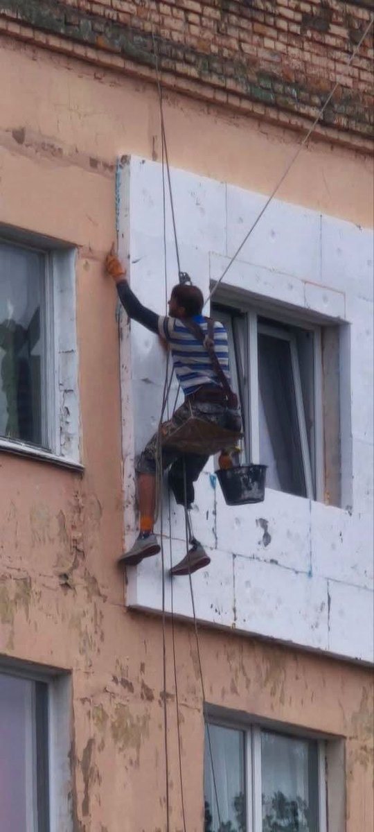 InUKRofficial's tweet photo. Kyiv region. A man with a prosthetic leg working high above the ground during yet another attack on the city, insulating the facade of an apartment building and preparing it for what could be a hard winter. https://t.co/MLRWgTOtrS