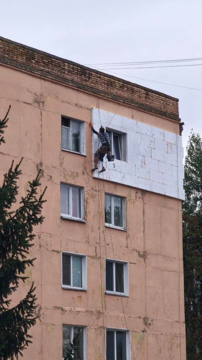 InUKRofficial's tweet photo. Kyiv region. A man with a prosthetic leg working high above the ground during yet another attack on the city, insulating the facade of an apartment building and preparing it for what could be a hard winter. https://t.co/MLRWgTOtrS