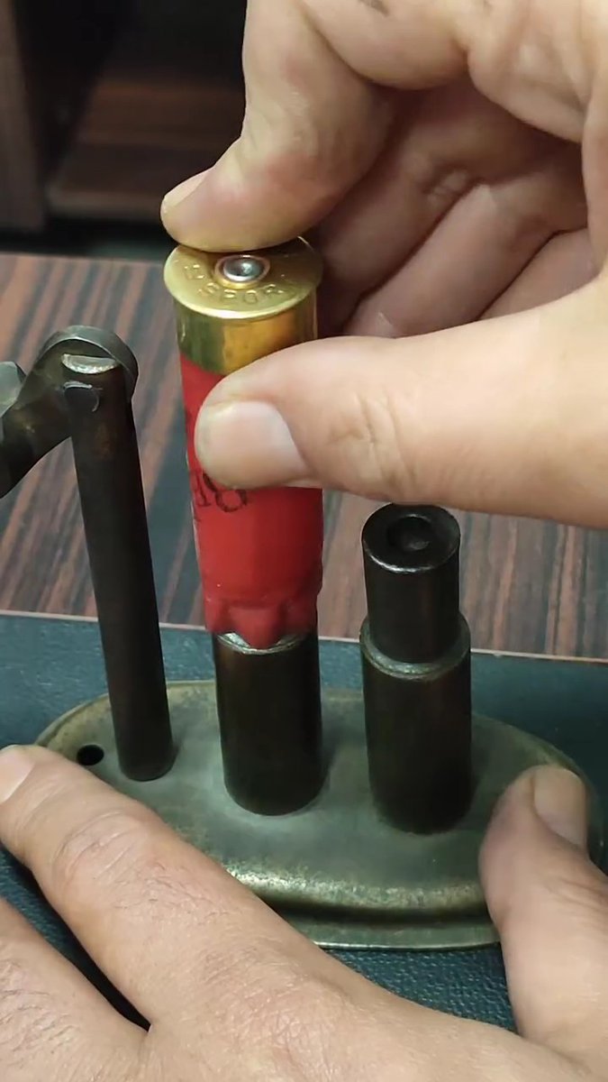 A person's hand presses a red shotgun shell (marked "12 GA") down into a reloading press alongside another empty shell casing. The satisfying shot of the shell snapping into place likely explains the poster's comment about enjoying this repetitive reloading process.