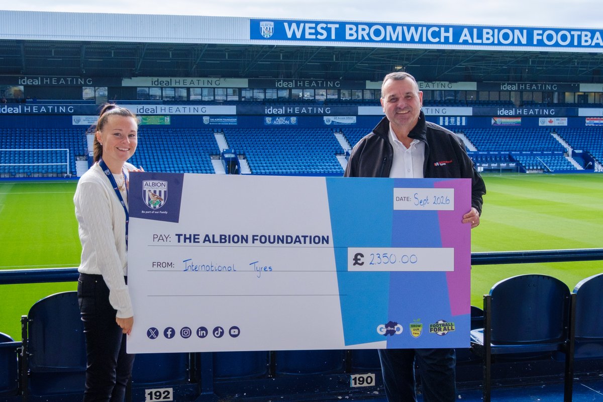 Chris Follows and Jayne Norton holding a large cheque at the The Hawthorns.