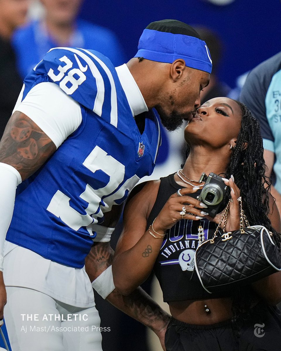 Jonathan Owens and Simone Biles kiss on the sidelines of a game