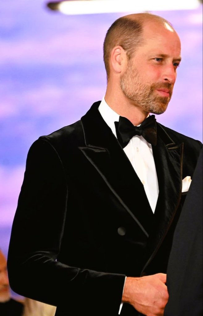 QLoTII's tweet photo. The man beside her

He was in black tie, which he wears like someone who would rather be in a flight suit, and he could not stop looking at her. That is not a line. Anyone who has watched him on these carpets for fifteen years knows the two versions of William: the public one, who does the hand-shaking and the polite enquiries, and the private one, who appears for a second when she laughs and then vanishes again behind the job. On Tuesday the private one kept appearing. He stood a half-step behind her on the carpet, where the light was hers, and let her have it.