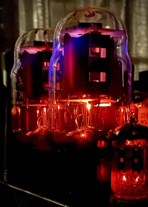 cqcqcqdx's tweet photo. Vacuum tubes glowing with a characteristic warm filament orange-red and a subtle fluorescence or blue glow on the glass envelope. https://t.co/1LX3Rl4G85