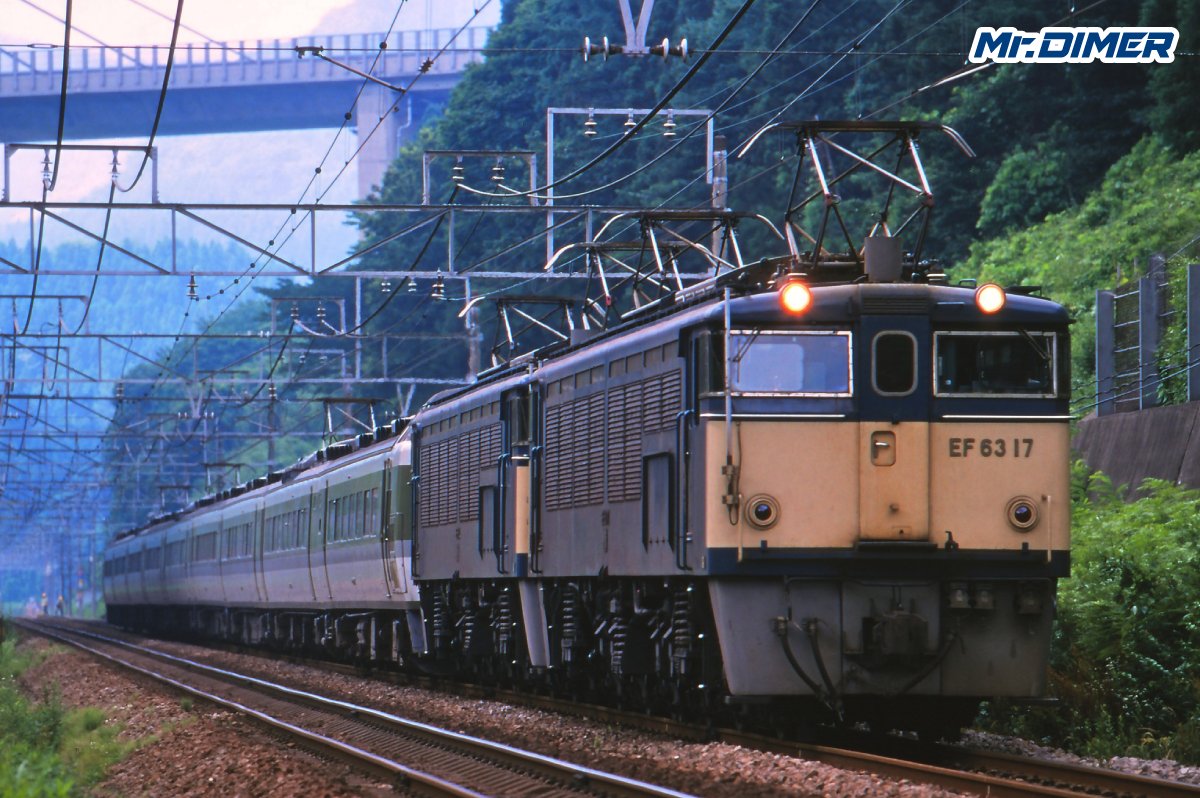 MrDIMER_X's tweet photo. 【鉄道を通す場所じゃない】それでも人々は碓氷峠に線路を敷いた

群馬県・横川と長野県・軽井沢。

その間、わずか11.2km。

いま地図だけを見れば、
「そんな短い区間が、なぜ日本の鉄道史にこれほど名を残したのか」
と思うかもしれません。

理由は単純です。
ここは、鉄道を通すにはあまりにも険しかった。

横川と軽井沢の標高差は約553m。
最大勾配は66.7‰。

1000m進む間に66.7m上る。

現在の鉄道でも強烈な数字ですが、
これを明治の鉄道技術で越えようとしたのです。

しかも、
「少し遠回りして緩い坂にしよう」では済まなかった。

東京と信越地方、さらに日本海側を結ぶ幹線を一本につなぐため、
どうしても碓氷峠を越えなければならなかったのです。

1885年、
鉄道は上野から横川まで到達。
一方、長野側からも鉄道建設は進みました。

最後に残った壁が、
横川―軽井沢間でした。

普通の機関車では、
車輪とレールの摩擦だけで66.7‰を安全に上り下りするのは難しい。

そこで採用されたのが「アプト式」。
線路中央に歯形のラックレールを敷き、
機関車側の歯車を噛み合わせ、
文字通り山をよじ登る方式です。

1893年4月1日。

ついに横川―軽井沢間が開通しました。

しかし、
「開通した」の四文字では、この工事の凄まじさは伝わりません。
約11.2kmの山中に、
26か所のトンネルと18基の橋梁。

それまで日本の鉄道建設は、
比較的平坦な場所を中心に進められていました。

碓氷峠は違った。

山を削り、
岩盤を穿ち、
谷を越え、
レンガを積み、
線路が通る場所そのものを新たに造らなければならない。

日本が、
本格的な山岳鉄道建設へ踏み込んだ場所の一つでした。

象徴が、
現在も残る碓氷第三橋梁、通称「めがね橋」です。

高さ約31m。
4連のレンガアーチ。
使用されたレンガは200万個以上ともいわれます。

今では美しい鉄道遺産として眺められるこの橋も、
もともとは観光のための建造物ではありません。
列車を峠の向こうへ通す。

ただそのために、
明治の人々が山の中へ築いた巨大なインフラでした。

そして、
苦労は線路を造ったところで終わりません。
66.7‰では、
登ること以上に「安全に下る」ことも難しい。

列車が加速しすぎれば、止められない。

さらに、
蒸気機関車で長いトンネルを抜ければ、
煤煙が乗務員を苦しめる。

線路だけではなく、
「どう走らせるか」まで考えなければ、
この峠は越えられなかったのです。

そのため碓氷峠では、
機関車、ブレーキ、運転方法、電力設備まで、
峠を越えるための独自の技術が積み重ねられていきます。

1912年には横川―軽井沢間を電化。

幹線鉄道としては日本初の電化であり、
碓氷峠は山岳鉄道であると同時に、
日本の鉄道技術が大きく前進する実験場のような場所にもなりました。

しかし戦後輸送量が増えると、
今度はアプト式そのものが大きな壁になります。

列車は遅い。
輸送力にも限界がある。
日本海側と首都圏を結ぶ幹線として見ると、
たった11.2kmの峠越えが、
信越本線全体のボトルネックになっていきました。

そこで国鉄が次に挑んだのは、
さらに大胆な方法です。

歯車を使わず、
66.7‰を越える。

1963年、
碓氷新線が完成。

新たに開発されたEF63形電気機関車によって、
一般的なレールと車輪の粘着力だけで峠を越える時代が始まります。

9月30日をもってアプト式は廃止。
翌10月1日から新線へ完全移行しました。

それでも、
碓氷峠が「普通の鉄道」になったわけではありません。
峠を越える列車にはEF63を連結する。

一部の電車には、
EF63と力を合わせて走るための協調運転装置まで搭載する。

鉄道が山を征服したのではありません。
時代ごとの最新技術を持ち込みながら、
列車の側が、
最後までこの山に合わせ続けたのです。

そして1997年9月30日。

長野新幹線開業を翌日に控え、
信越本線・横川―軽井沢間はその役目を終えました。

1893年の開業から104年。

アプト式。
電化。
新線。
EF63。
協調運転。

時代が変わるたび、
人々は新しい方法を考え、
それでもこの峠に列車を通し続けました。

なぜ、そこまでして鉄道を通したのか。

なぜ、100年以上もこの難所と戦い続けたのか。

廃止から29年を経て9月30日から始まる新連載
【日本の鉄道難所】
「鉄路をつなげ――自然に挑んだ鉄道マンたち」。

第1章は、
碓氷峠・横軽です。

66.7‰。

たった三文字の数字の裏に、
どれほどの人間の執念と技術が積み重なっていたのか。

鉄道を通す場所じゃない。

それでも、
人々はここに線路を敷いた。

1893年4月1日の開業から、
1997年9月30日の廃止まで。

その104年6か月に及ぶ碓氷峠の鉄路の歴史を、
ここから辿ります。

（マイミー）