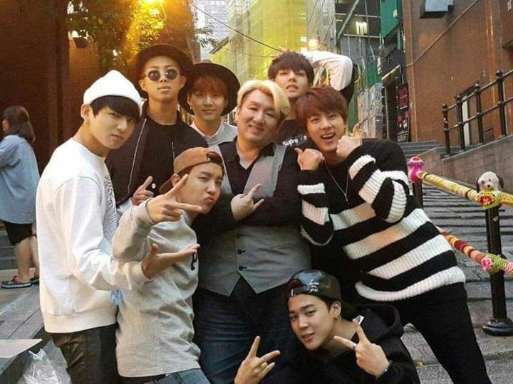 Eros_AgustD's tweet photo. บทสรุป 7คน7วัน7เรื่อง(ไถ่ไปอ่านก่อนได้)….อะไรคือ “แรงส่ง” ที่ทำให้รถไฟขบวนนี้วิ่งไกลเกินกว่ารางที่Bang Si-Hyuk และ BigHit เคยวางไว้ : Saveไว้อ่านตอนกิน☕️ ใครเห็นรูปแล้วเริ่มด่าในใจก็วางBiasก่อนอ่าน

ถ้าใครรู้จัก BTS มานานพอ จะรู้ว่าความสัมพันธ์ระหว่างอีอ้วนบังชีกับวงนี้ไม่ใช่เรื่องง่ายแบบ “ผู้สร้างสร้างวง → วงดัง → จบ” เพราะตั้งแต่ก่อนเดบิวต์จนถึงวันนี้ อีอ้วนบังชีเปลี่ยนแผนมาแล้วหลายรอบ สมาชิกทั้ง 7 คนก็เติบโตจนมีความคิดและเส้นทางของตัวเอง ขณะเดียวกันยังมีคนอีกกลุ่มหนึ่งที่ค่อย ๆ เข้ามาเปลี่ยนสมการทั้งหมด นั่นคือ ARMY แต่ถ้าจะเล่าเรื่องนี้ให้ครบจริง ๆ เราอาจต้องมองแบบรอบด้านว่ามันประกอบด้วย คนวางระบบ + ศิลปิน 7 คน + แฟนคลับนับล้านที่ช่วยกันผลักรถไฟขบวนนี้ไปข้างหน้า

👉 อดีต

ก่อนจะมี BTS แบบที่เรารู้จัก อีอ้วนบังชีมีแค่เด็กแรปเปอร์คนหนึ่งกับความคิดว่า “วงนี้ควรเป็นฮิปฮอป”

จุดเริ่มต้นของ BTS ไม่ได้เกิดจากแผนสร้างบอยกรุ๊ปที่ครบสูตร แต่เริ่มจาก RM ซึ่ง Pdogg นำเดโมมาให้อีอ้วนบังชีฟัง แล้วเขามองเห็นศักยภาพของเด็กคนนี้จนตัดสินใจดึงเข้ามาเป็นแกนสำคัญของโปรเจกต์ เดิมทีสิ่งที่อีอ้วนบังชีคิดไว้ใกล้เคียงกับ hip-hop crew มากกว่า idol group เน้นแรป การทำเพลง และตัวตนของศิลปิน แต่เมื่อสถานการณ์เปลี่ยน เขาก็เปลี่ยนโจทย์ด้วย เพราะถ้าต้องการให้ข้อความของเด็กกลุ่มนี้ไปถึงคนจำนวนมาก การอยู่ในระบบไอดอลที่มีทั้งเพลง Performance และเวทีขนาดใหญ่ย่อมเปิดประตูได้กว้างกว่า นั่นทำให้เด็กฝึกสายฮิปฮอปบางคนเลือกออกไป เพราะสิ่งที่กำลังจะกลายเป็น BTS ไม่ใช่สิ่งที่พวกเขาสมัครเข้ามาตั้งแต่แรกแล้ว

RM, SUGA และ J-Hope จึงกลายเป็นแกนฝั่งฮิปฮอปที่เหลืออยู่ ก่อนจะมี Jin, Jimin, V และ Jungkook เข้ามาประกอบกันจนเกิดวงที่ตอนแรกก็ดูเหมือนเอาคนละโลกมายัดไว้ในห้องเดียวกัน แต่กลับกลายเป็นส่วนผสมที่ทำให้ BTS มีเอกลักษณ์ขึ้นมาเอง RM เป็นแกนด้านความคิดและการสื่อสาร SUGA มีความเข้มข้นทางดนตรี J-Hope แข็งแรงด้าน Performance และพลังของทีม Jin ค่อย ๆ สร้างพื้นที่ของตัวเอง Jimin นำภาษาการเต้นที่แตกต่างเข้ามา V มีเสน่ห์แบบที่ไม่จำเป็นต้องพยายาม ส่วน Jungkook เป็นเด็กที่มีศักยภาพสูงมากแต่ต้องค่อย ๆ ทลายกำแพงความขี้อายของตัวเอง

สิ่งที่น่าสนใจคืออีอ้วนบังชีเองก็ไม่ได้มองสมาชิกทุกคนแล้วพูดว่า “ใช่เลย นี่แหละสมบูรณ์แบบ” ตั้งแต่วันแรกด้วยซ้ำ อย่างเช่น จีมินที่เขายอมรับภายหลังว่าเคยมีความกังขา เพราะพื้นฐานการเต้นของจีมินมาจากโมเดิร์นแดนซ์และยังไม่แน่ใจว่าจะเข้ากับแนวทางของวงได้แค่ไหน แต่เด็กคนนี้ก็ไม่ได้เอาความกังขานั้นกลับบ้านแล้วร้องไห้ใส่หมอน เขาใช้เวลาที่เหลือพิสูจน์ตัวเองจนสุดท้ายกลายเป็นหนึ่งในคนที่ทำให้ Performance ของ BTS มีลายเซ็นที่ชัดเจนที่สุด

พี่โฮปเองก็เคยเกือบเดินออกจากทีมก่อนเดบิวต์ ส่วนพี่จินเข้ามาโดยแทบไม่มีพื้นฐานไอดอลและต้องฝึกจากจุดที่คนอื่นนำหน้าไปมาก ขณะที่จองกุกเป็นเด็กขี้อายจนต้องหาวิธีเปิดโลกให้เขาออกจากเปลือก ส่วนพี่วีก็ถูกเก็บเป็นสมาชิกปริศนาก่อนเดบิวต์เพราะบริษัทต้องการสร้างความอยากรู้ ทั้งหมดนี้ทำให้เห็นว่า BTS ไม่ได้เกิดจากการเอาคนที่ “พร้อมที่สุด” 7 คนมายืนเรียงกัน แต่เกิดจากการเอาคนที่แตกต่างกันมาก 7 คนมาอยู่ในระบบเดียวกัน แล้วปล่อยให้แต่ละคนค่อย ๆ หาพื้นที่ของตัวเองจนกลายเป็นทีม

ส่วนพี่ก้าก็เป็นหลักฐานมีชีวิตว่าอย่าเชื่อคำสัญญาของอีอ้วนบังชีง่าย ๆ🤣ยุนกิเข้ามาด้วยความตั้งใจอยากเป็นแรปเปอร์และโปรดิวเซอร์มากกว่าอยากเป็นไอดอล และเรื่องที่ถูกหยิบมาแซวกันจนกลายเป็นมุกประจำก็คือคำพูดในช่วงแรก ๆ ว่าไม่จำเป็นต้องเต้นหนักมาก แต่ดูสิ่งที่เกิดขึ้นกับชีวิตพี่ก้าหลังจากนั้น~จากคนที่คิดว่าจะได้ยืนแรปแบบเท่ ๆ กลายเป็นคนที่ต้องผ่าน choreography ระดับที่บางครั้งคนดูยังเมื่อยแทน 😂 เรื่องนี้เลยเป็นมุกที่ขำเพราะมันสะท้อนความจริงอย่างหนึ่งว่า แม้แต่คนสร้างเองก็ไม่ได้รู้ตั้งแต่ต้นว่า BTS จะกลายเป็นอะไร

ต่อ👇🏻