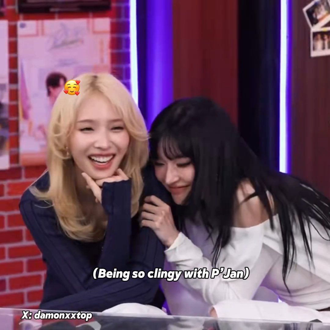 Two K-pop idols smiling and cuddling closely in what appears to be a studio setting, with a subtitle reading "(Being so clingy with P'Jan)" and a Twitter handle "damonxxtop" visible.