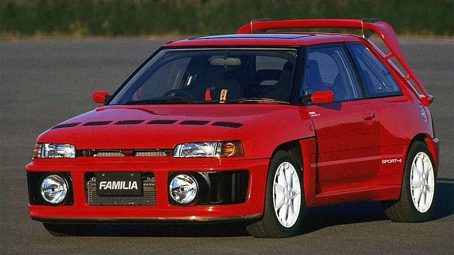 car_kobanashi's tweet photo. マツダ ファミリア SPORT-4（1989 日本）
1989年の第28回東京モーターショーで公開された「ファミリア SPORT-4（スポルト4）」は、WRC（世界ラリー選手権）参戦を見据えて開発されたコンセプトカーである。同年に登場した7代目ファミリア（BG型）の3ドア「GT-X」をベース���開発。当時グループAで猛威を振るっていたランチア デルタに対抗すべく、将来の市販化とホモロゲーション取得を視野に置いた過激なスタディモデルとして企画された。

パワートレーンには、1.8リッター直列4気筒DOHCターボを搭載。大型インタークーラーの採用や過給圧の引き上げ、吸排気系の徹底的な見直しにより、ベース車の180psから220psへと出力を高めた。駆動系には市販型GT-Xで採用されていたフルタイム4WDシステムを踏襲。遊星歯車式センターデフにより前後駆動力配分を旋回性重視の「前43：後57」に設定し、センターおよびリアデフにビスカスLSDを装備、4輪ABSも組み込まれた。単なる展示用モックアップにとどまらず、走行可能��実動車両として仕立てられていた。

外観は、大型丸型フォグランプを配した専用フロントバンパーや張り出した前後ブリスターフェンダーによって全幅1740mmの3ナンバーサイズへ拡幅され、ルーフ後端からは巨大なハイマウント型ルーフウイングが屹立する。サスペンションはアーム延長によりトレッドを前1490mm／リア1495mmへと大幅に拡大。冷却ルーバーを備えたボンネットには当時先進的なCFRP（カーボンファイバー）素材が奢られ、強固なロールケージや大型エアロパーツを装着しながらも、徹底した軽量化により車重はベース車のGT-Xと同等の1160kgに抑えられていた。

量産化は見送られたが、当モデルで追求されたアグレッシブな冷却レイアウトや軽量化、空力設計の知見は、1992年にグループAホモロゲーションモデルとして登場した「ファミリア GT-R」へと受け継が��た。グループBマシンを彷彿とさせる武闘派の出で立ちは、ラリー黄金期におけるマツダの強い闘志と技術的野心を伝えるコンセプトモデルである。#車小噺