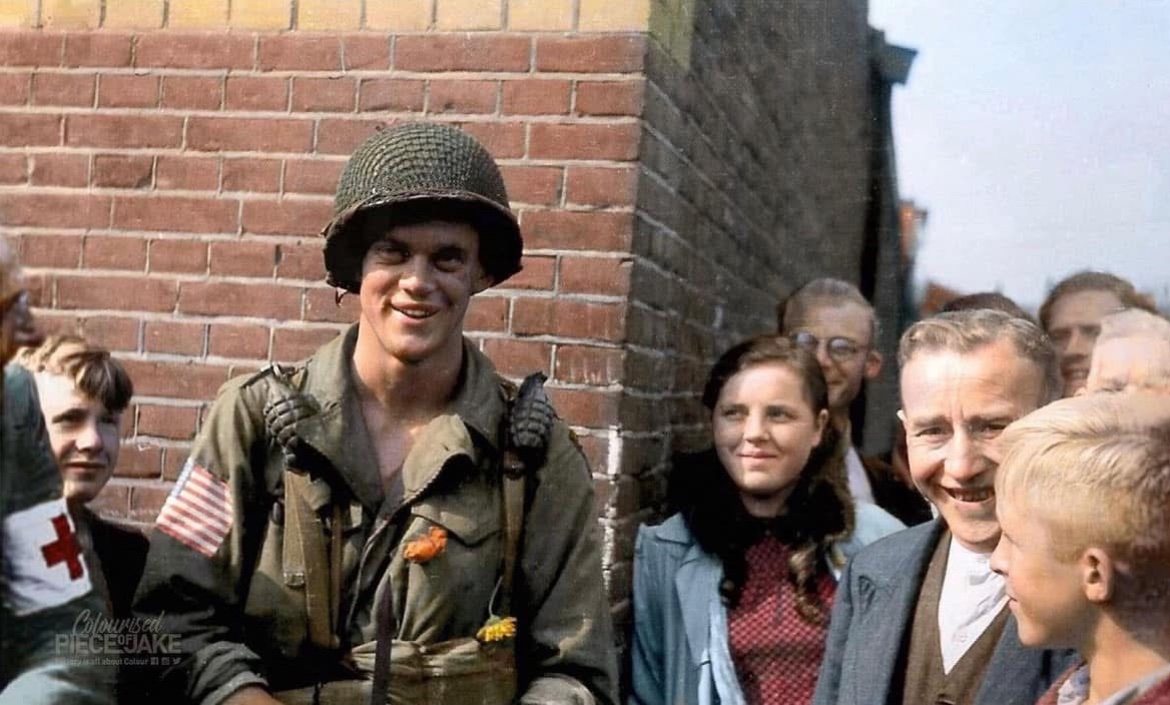 Jason_R_Burt's tweet photo. In September of 1944, Easy Company paratrooper Pfc. David Webster poses for the camera with the local population in Eindhoven, Netherlands. 🪂

@PieceJake on the colorization 🎨 https://t.co/fwqgttJ6Sf