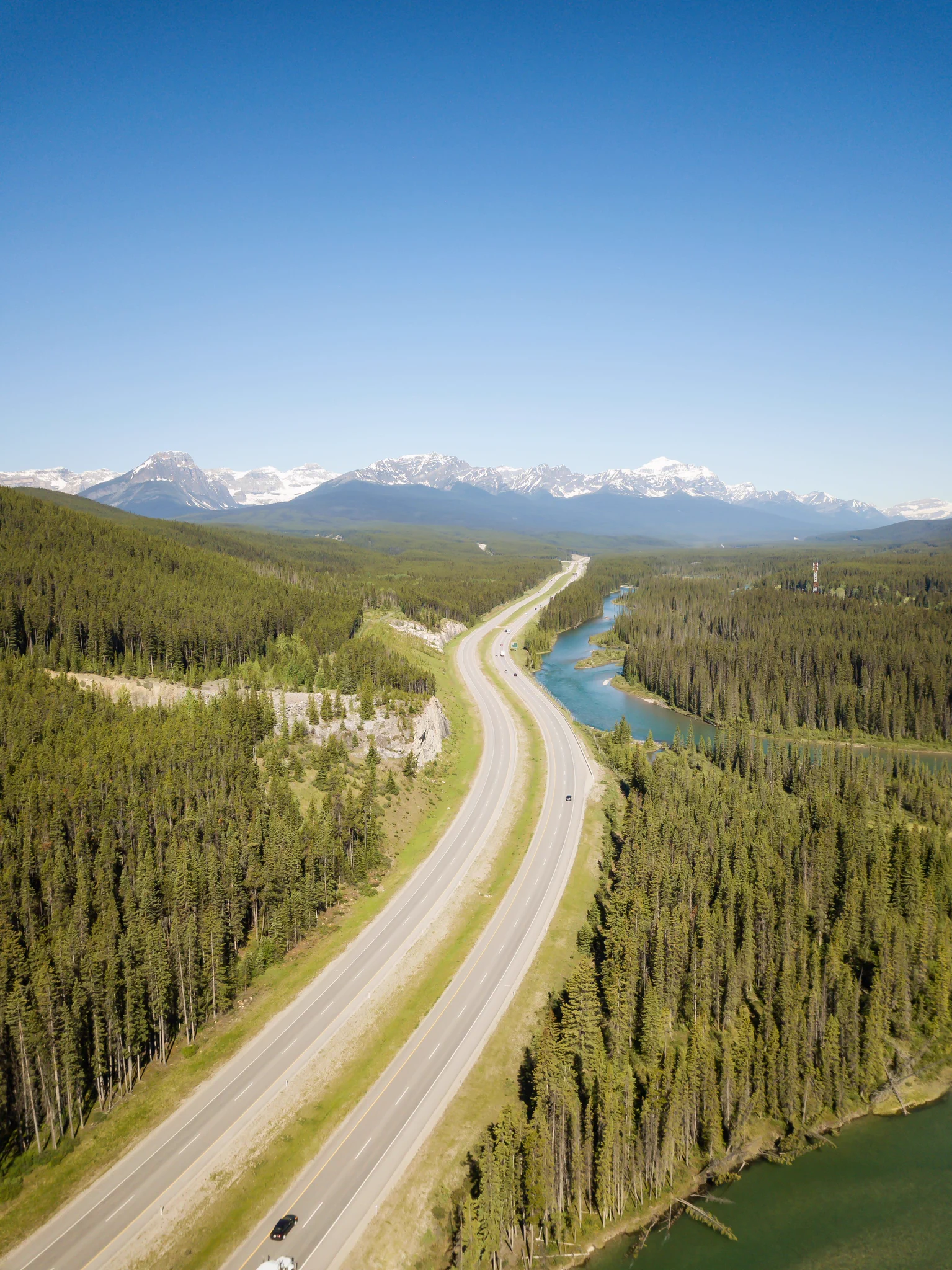Aerial landscape view of a highway in Canadian Rockies during a vibrant sunny day. 
