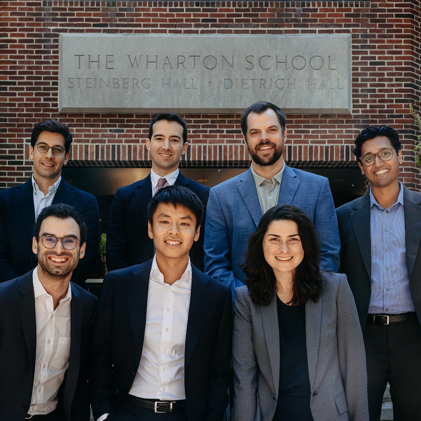 A group of new faculty members pose in front of Steinberg-Dietrich Hall at Wharton