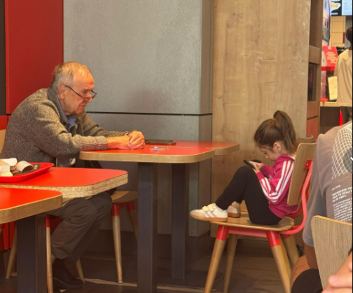 00devinho's tweet photo. This deeply sad image has gone super viral of a grandfather sitting just a few feet away from his granddaughter, while she is completely absorbed in her phone.

https://t.co/P3uNhjSvSj

Other viral post today:
https://t.co/bRMzvp5JA8

https://t.co/CPlYfL5bdD

To many people, the image represents more than just one moment between a grandfather and granddaughter, it represents a generation growing up in a world where our attention is constantly being pulled toward screens.

What makes it so emotional is the contrast in their lives. The grandpa has probably very little time left, she has so much of hers still ahead of her. Yet in this moment, the limited time they have together is wasted spent looking at a screen.

Almost everyone can recognize some version of it. We have become accustomed to checking our phones while eating, talking to family, sitting with friends, or spending time with people we care about. We are more connected to the internet than ever, yet sometimes less present with the people sitting right beside us.

And perhaps the saddest part is that we often don’t realize the value of a moment until it has already become a memory.