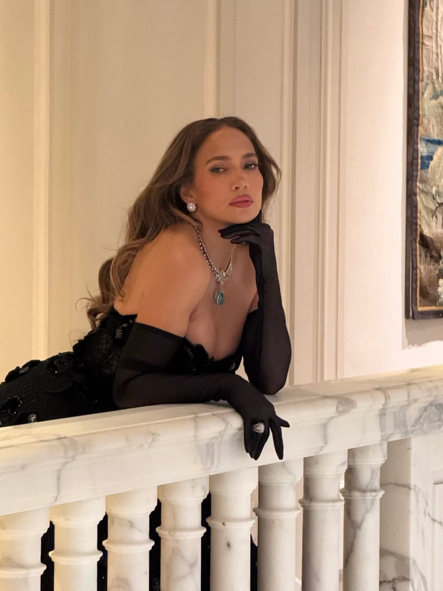 popbuzzz_'s tweet photo. Jennifer Lopez stuns at the Vogue World 2026: Milano in the Galleria Vittorio Emanuele II wearing a strapless black Dolce & Gabbana tulle ballgown with floral sequin appliqués, sheer opera gloves, pointed slingbacks, and a standout 74-carat turquoise pendant necklace.

The star was pulled from the front row by Italian tennis player Lorenzo Musetti for a surprise runway dance moment evoking classic Italian cinema like La Dolce Vita, highlighting the event’s celebration of Made in Italy craftsmanship during Milan Fashion Week.