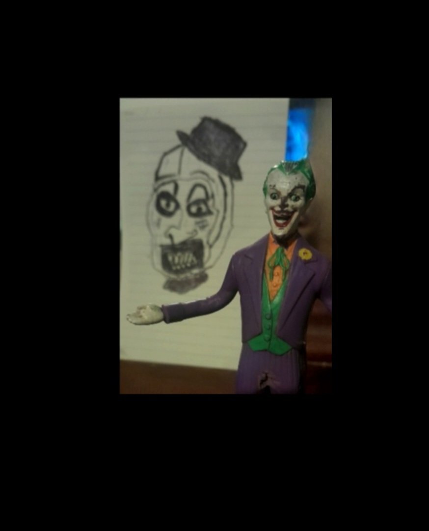 ArttheClownart's tweet photo. "Why so serious?" 🃏🩸This beat-up old Joker toy is either recovering from Batman or about to get stabbed in the back by my new Art the Clown drawing. Looks awesome standing in front of it! Had David Howard Thornton in mind for this. 🤫🤡

#terrifier
#arttheclown
#joker
#joker https://t.co/NEI9317t1b