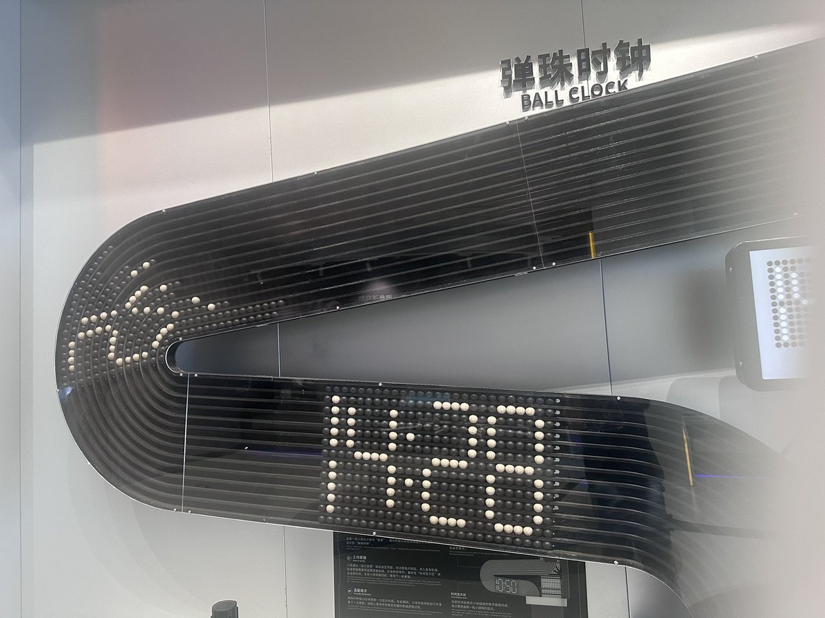 akita11's tweet photo. ボールで時計。白と黒がランダムにならんで上がっていき、文字の形になるように選んで落とすのか。なるほど。
 #SZdiary https://t.co/qdE4DJP9Gh