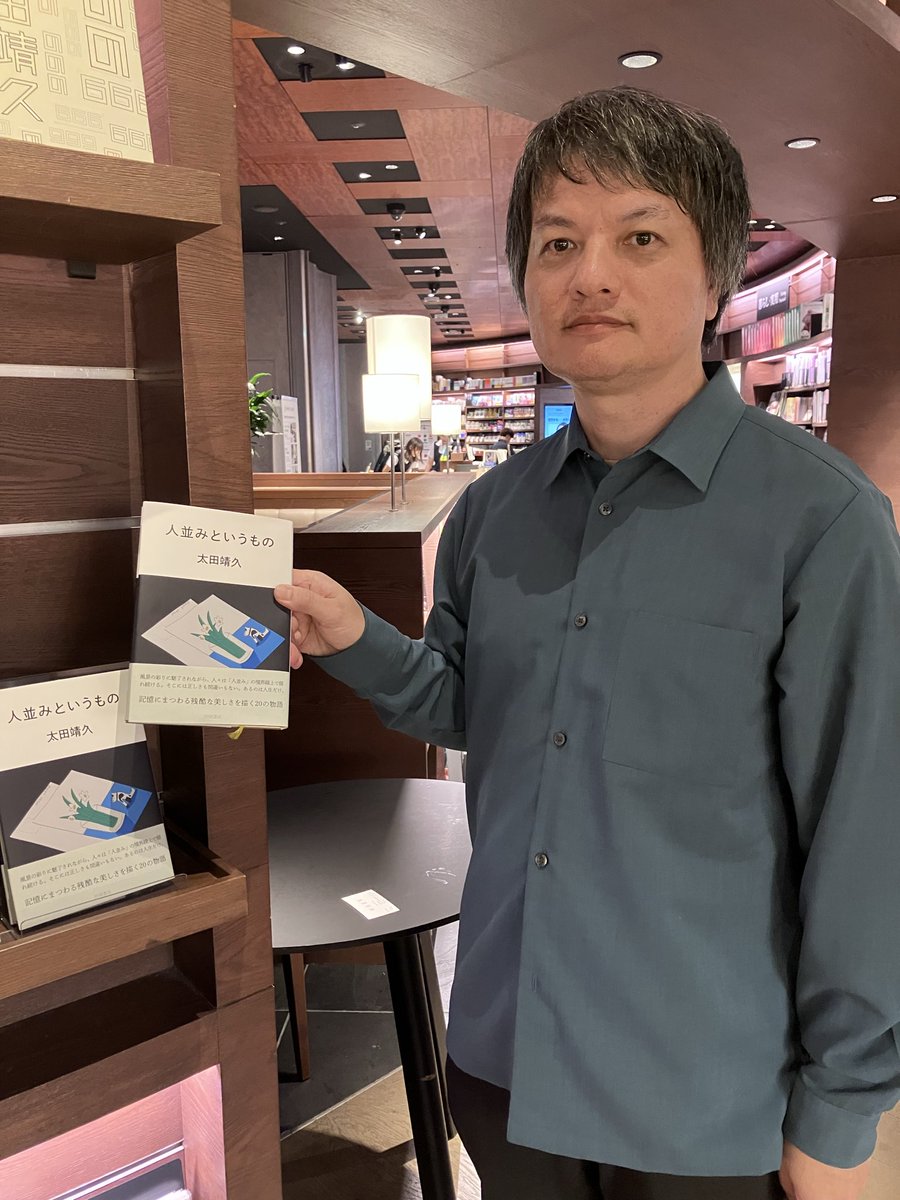 棚の前で先行販売中の『人並みというもの』を手に立つ太田靖久さん