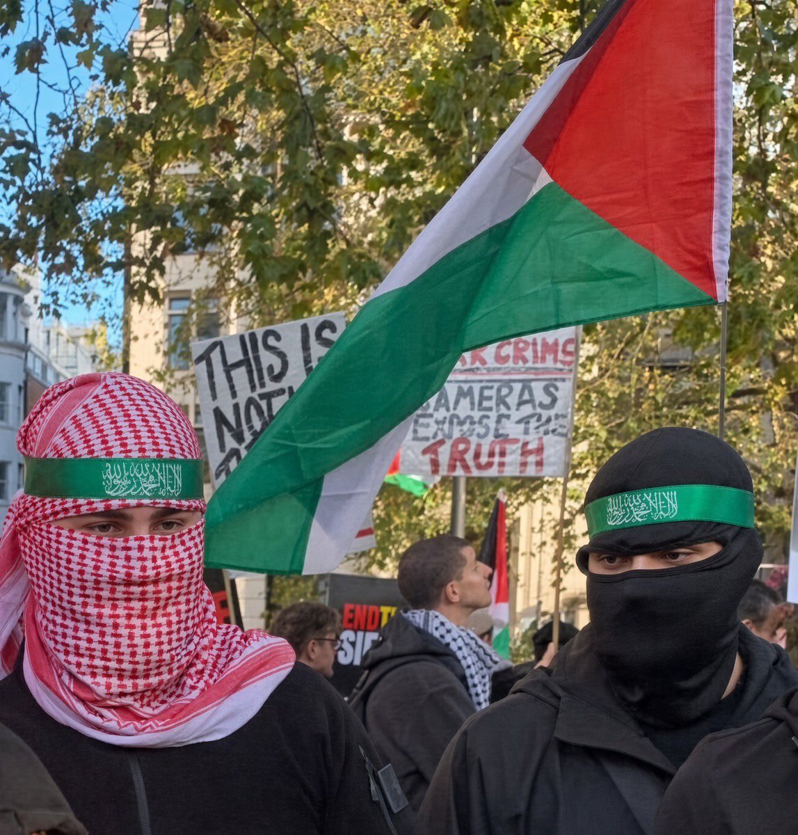 benonwine's tweet photo. Why are the government and police fine with this on British streets?

Faces covered. Green headbands that look exactly like the ones Hamas fighters wear. 

Hamas is a banned terrorist organisation in the UK. 

Wearing clothing or items “in such a way as to arouse reasonable suspicion” of support for them is a criminal offence. People have already been convicted for it.

Yet this is still treated as normal. Why? 
Especially when Patriots are persecuted and targeted because they wear balaclavas.
