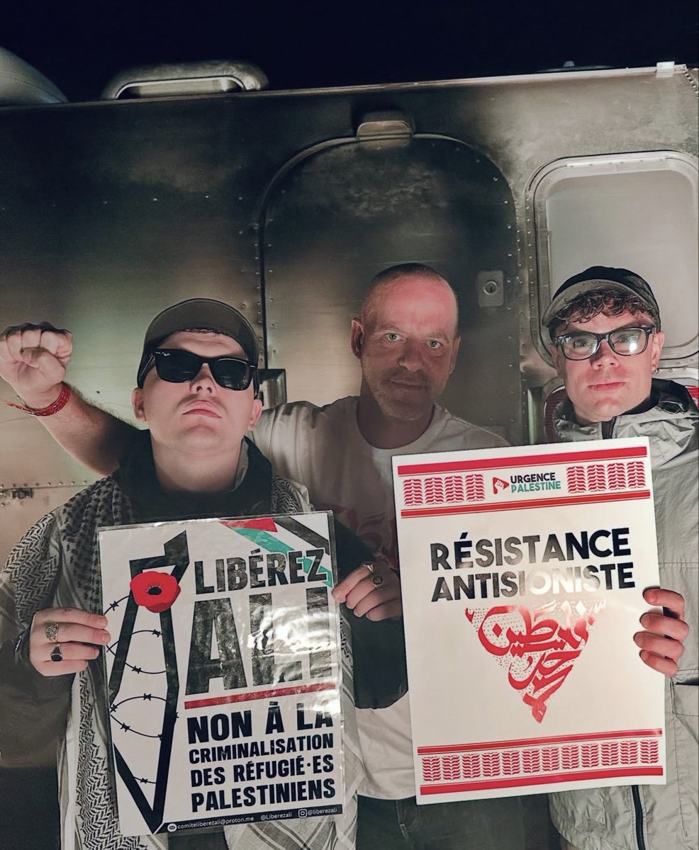 HeidiBachram's tweet photo. Here’s Kneecap at a festival south of Paris yesterday holding posters calling for the release of a Palestinian prisoner held on remand in France for ATTEMPTED MURDER of Israelis and terrorism. Shameful. https://t.co/QFCGXkFr6l