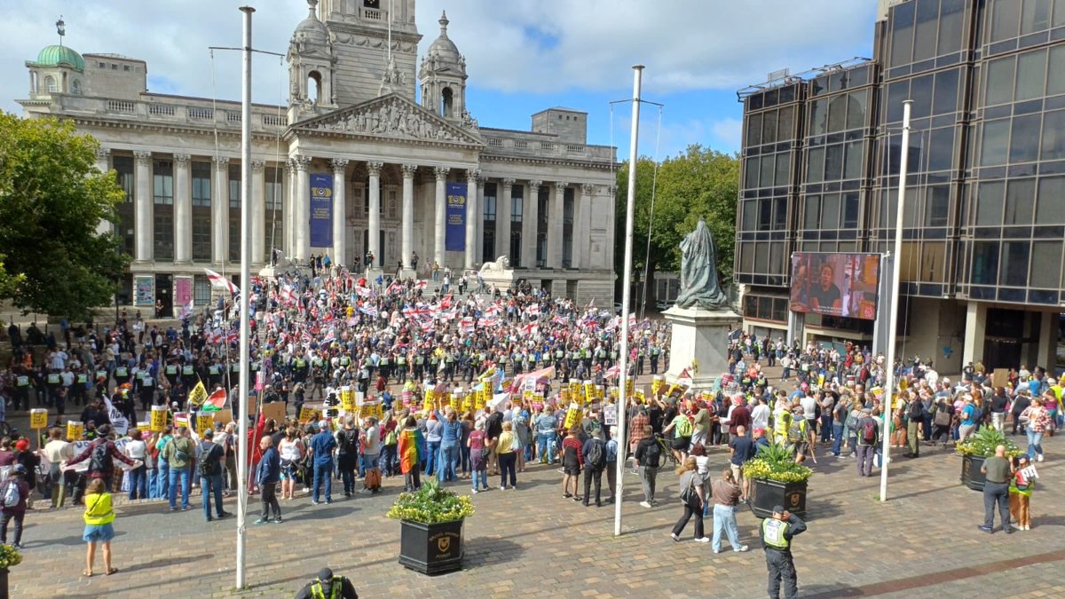 JamesBrian29916's tweet photo. This picture was captured today at the Portsmouth protest. 

It is completely unedited. The field of view covers the entire area where both crowds were situated. It was taken from this view because the far left like to take pictures from the front of a crowd at low angles and later flood social media with captions like “outnumbering the far right.” 

As you can see from the picture, the far left are massively outnumbered (as they always are), and it gives a sense of the general feeling in the country. Let’s not forget that almost all of the people on the far left are also transported into the area by bus, as opposed to the patriots who are all local residents.