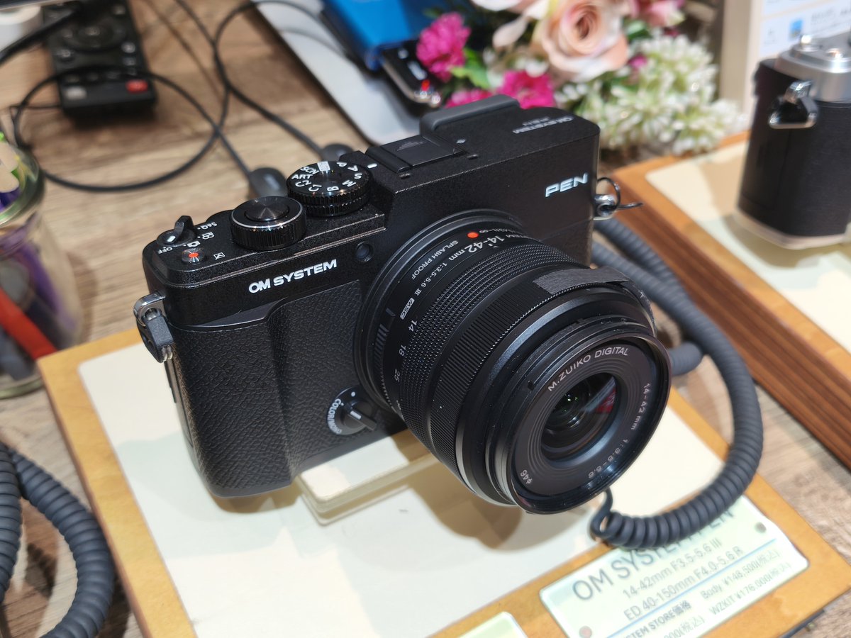 ogizaru_tob8000's tweet photo. ”OM SYSTEM PEN”見てきました。

前提として、ボディ単体で13万円台で購入できる価格のボディであることを覚えておいてください。非常に良いカメラです。

1.外装デザインについて

　このカメラの外装デザインについてはSNS上で多くの意見が散見されます。まず、フイルム時代から続くOLYMPUS PENのロゴをリデザインされた担当者の方に敬意を表したいと思います。とても素敵なロゴマークだと感じました。ありがとうございます。

　その上で。パッと見特にシルバーで右上のデコが広く見えます。これはオリジナルのPEN-F系のオマージュで貼り革の位置が下がっていることに起因するものです。
　しかし、これによってPENロゴがシルバーの色の部分の上下中央かつOM SYSTEMロゴとも高さが揃った位置に配置されており、個人的には非常に完成度の高いデザインであると感じました。

　また、シルバーボディの質感は価格相応という印象を受けました。良くも悪くもです。
　確かにこの質感のボディが40万円で売られていたら、ライカで使われていたら。それは確かに不満足と言わざるを得ません。ただ13万円のカメラとしては明らかなチープさを感じることもなく、剛性感もしっかりしていました。他機種と比較するとOM-5 MarkIIやOM-3のシルバーと非常に近い印象を受けました。

(続く)