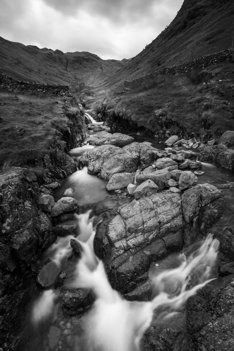 Rosswilson424's tweet photo. Stockley Bridge, looking back to Seathwaite. A grey, moody Borrowdale day where the beck did all the talking — long exposure turned the water to silk beneath a brooding sky. 🏔️🖤

#LakeDistrict #Borrowdale #BlackAndWhitePhotography https://t.co/HyPMdskeiY