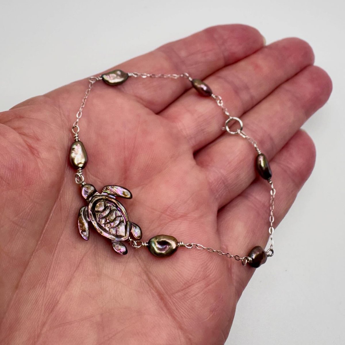 sanchezpedro2's tweet photo. Made another abalone sea turtle necklace! This one features deep purple tones paired with lustrous freshwater pearls in purple, green, and gold hues. The sterling silver bracelet is 8 inches long, with a 1–1. 5-inch extension available for an https://t.co/5oAQaQyHhC