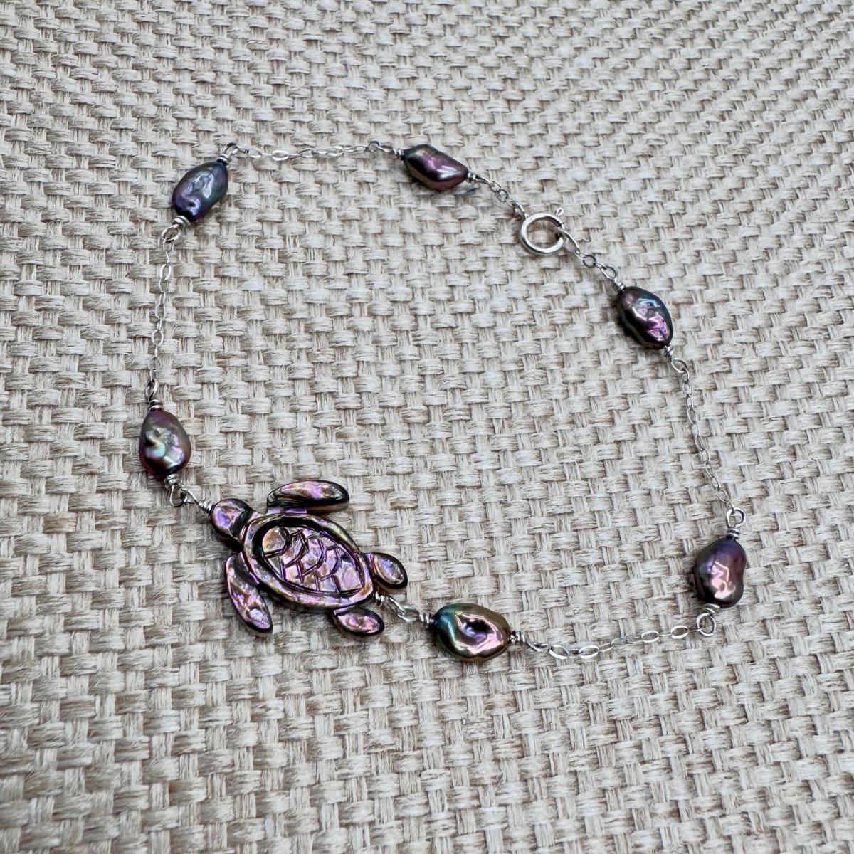 sanchezpedro2's tweet photo. Made another abalone sea turtle necklace! This one features deep purple tones paired with lustrous freshwater pearls in purple, green, and gold hues. The sterling silver bracelet is 8 inches long, with a 1–1. 5-inch extension available for an https://t.co/5oAQaQyHhC