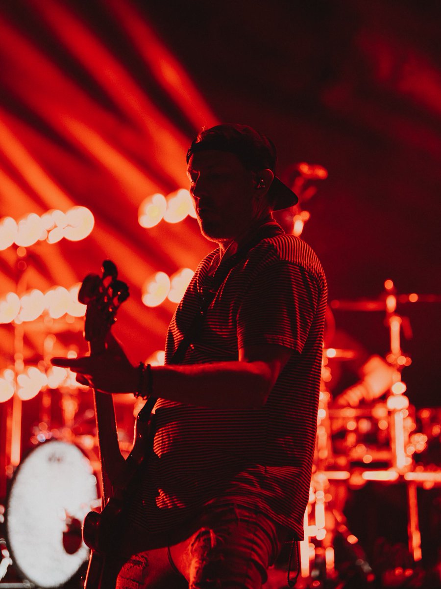 A musician silhouetted against red stage lights, playing a guitar.