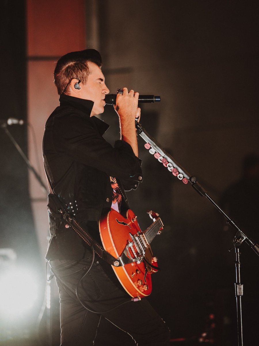 Musician holding a microphone and guitar while performing on stage.