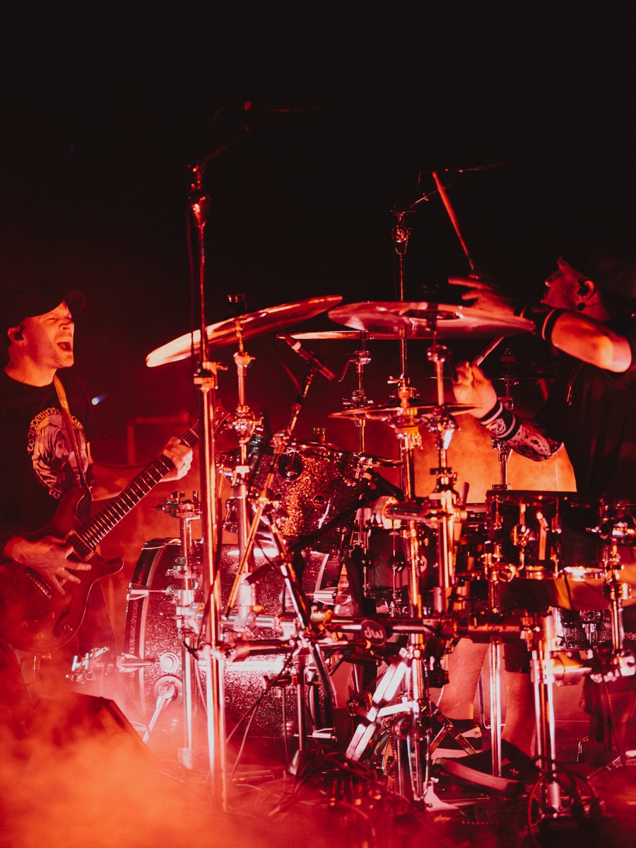 Band playing instruments on stage with dramatic red lighting.