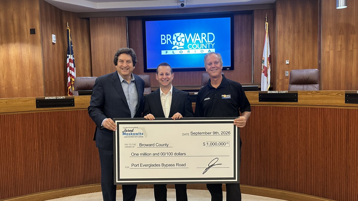 Three men holding ceremonial check with Broward County graphic and seating in the background. Message reads: 💰 A $1 million investment in Broward County’s transportation infrastructure!
Congressman Jared Moskowitz presented Broward County Mayor Mark Bogen and Commissioner Beam Furr with $1 million in federal funding for the Port Everglades Bypass Road.
The roadway provides a direct connection between State Road 84, U.S. 1 and SE 17th Street, allowing motorists to travel through the Port Everglades area without entering its secured facilities. It also provides improved access to the Broward Convention Center, Omni Hotel, and nearby businesses and beaches with the potential to reduce traffic congestion along SE 17th Street.