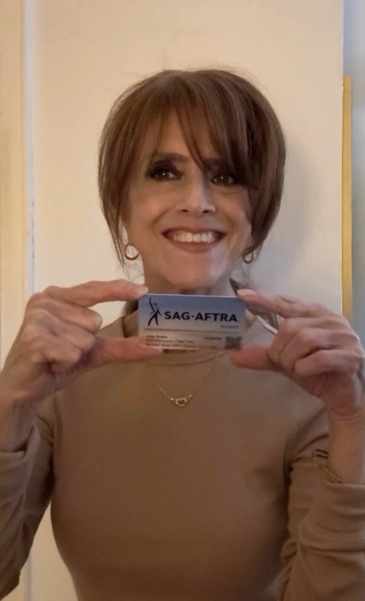 Judy Malka smiling and proudly holdingu p her SAG-AFTRA membership card.