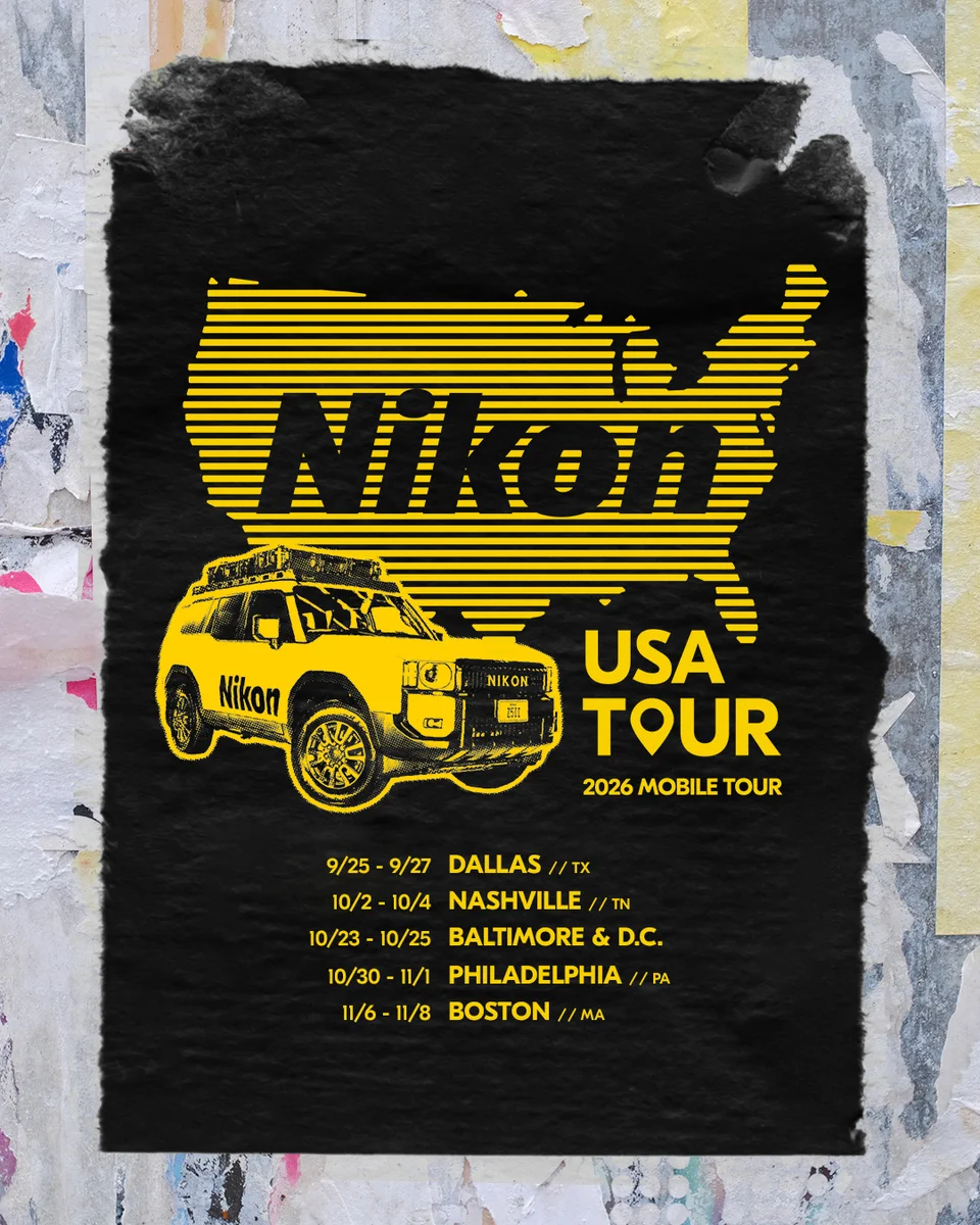 A black poster on a textured wall featuring a yellow silhouette of the United States, Nikon-branded vehicle and text that reads: "Nikon USA TOUR 2026 MOBILE TOUR 9/25-9/27 DALLAS // TX, 10/2-10/4 NASHVILLE // TN, 10/23-10/25 BALTIMORE/D.C., 10/30-11/1 PHILADELPHIA // PA, 11/6-11/8 BOSTON // MA"