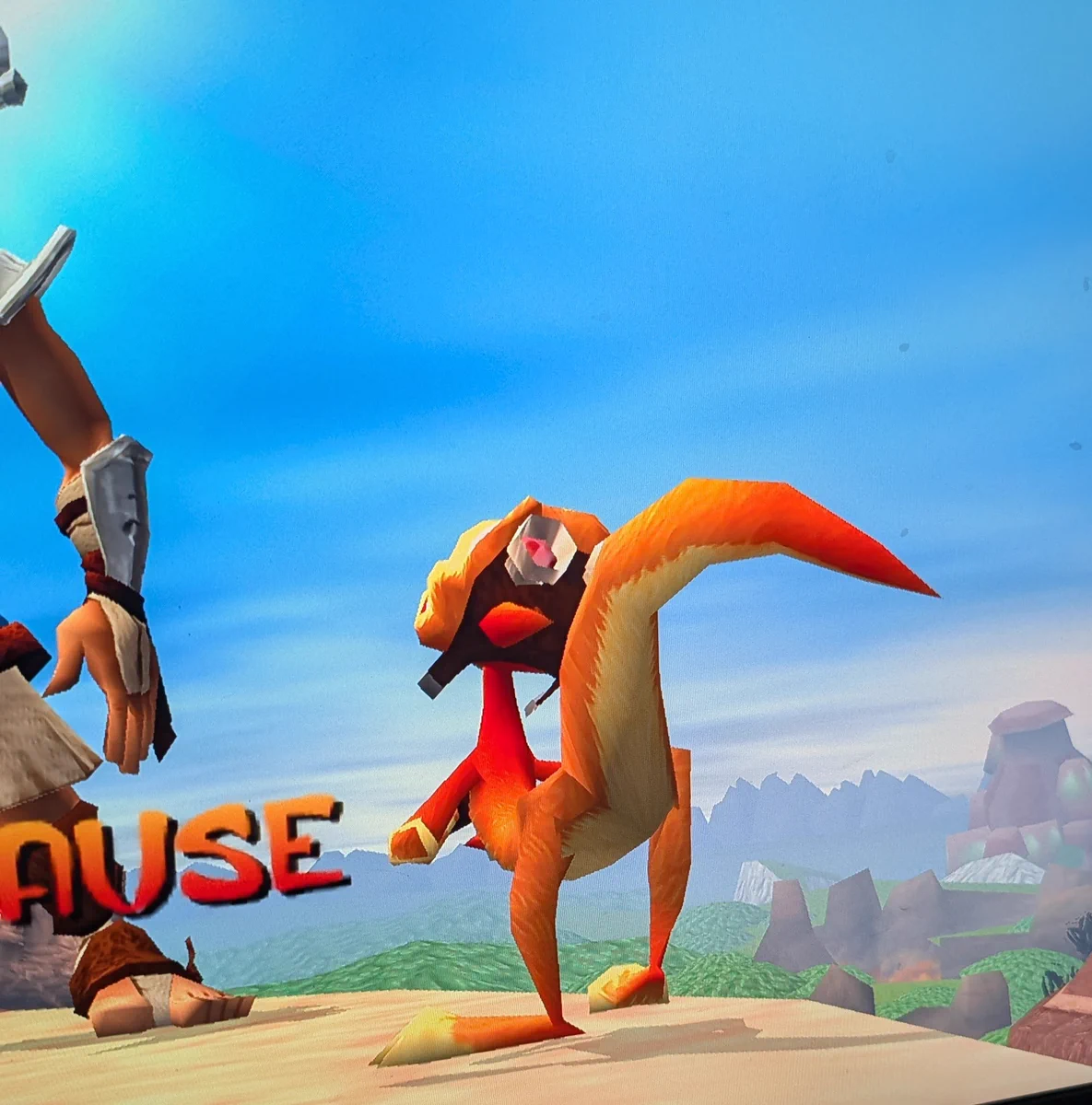 A screenshot of a video game pause screen featuring an orange ottsel, Daxter, leaning backward at a comical, unnatural angle next to Jak's leg.