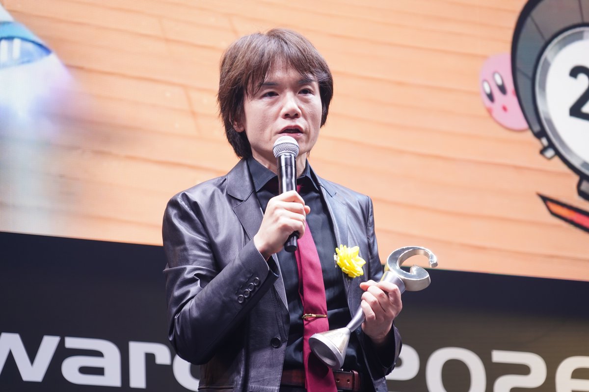 CoRRiENTE_top's tweet photo. 「日本ゲーム大賞2026」の優秀賞に、『カービィのエアライダー』が選ばれました！

『カービィのエアライド』以来、約22年ぶりとなる新作。独特なマシンを駆使するライドアクションで、「シティトライアル」では16人同時対戦、「ロードトリップ」では好きなライダーを選んで旅を楽しめます。簡単な操作ながら奥深い駆け引きが楽しめる点が支持され、受賞につながりました。

受賞コメントにはディレクターの桜井政博さんが登壇。続編を求める声が長年にわたって寄せられていたことを振り返り、「他に変わりのあるタイトルがなかったから」こそ、多くのユーザーに待ち望まれていたのではないかと語りました。

一方で、本作が「マリオカートの偽物」のように見られることもあると話すと、すかさず「マリオカートじ��ないんですよ。もうジャンルごと違いますから。ライドアクションです」と桜井さんらしいコメントも。会場からも笑いが起こりました。

16人同時対戦については、企画段階では「32人や60人もありえる」と書いていたものの、「ありえませんでした」と笑いを誘う一幕も。最後には、まだ遊んでいない人に向けて「ぜひプレイしていただいて、その変わったところを楽しんでいただければ」と呼びかけました。