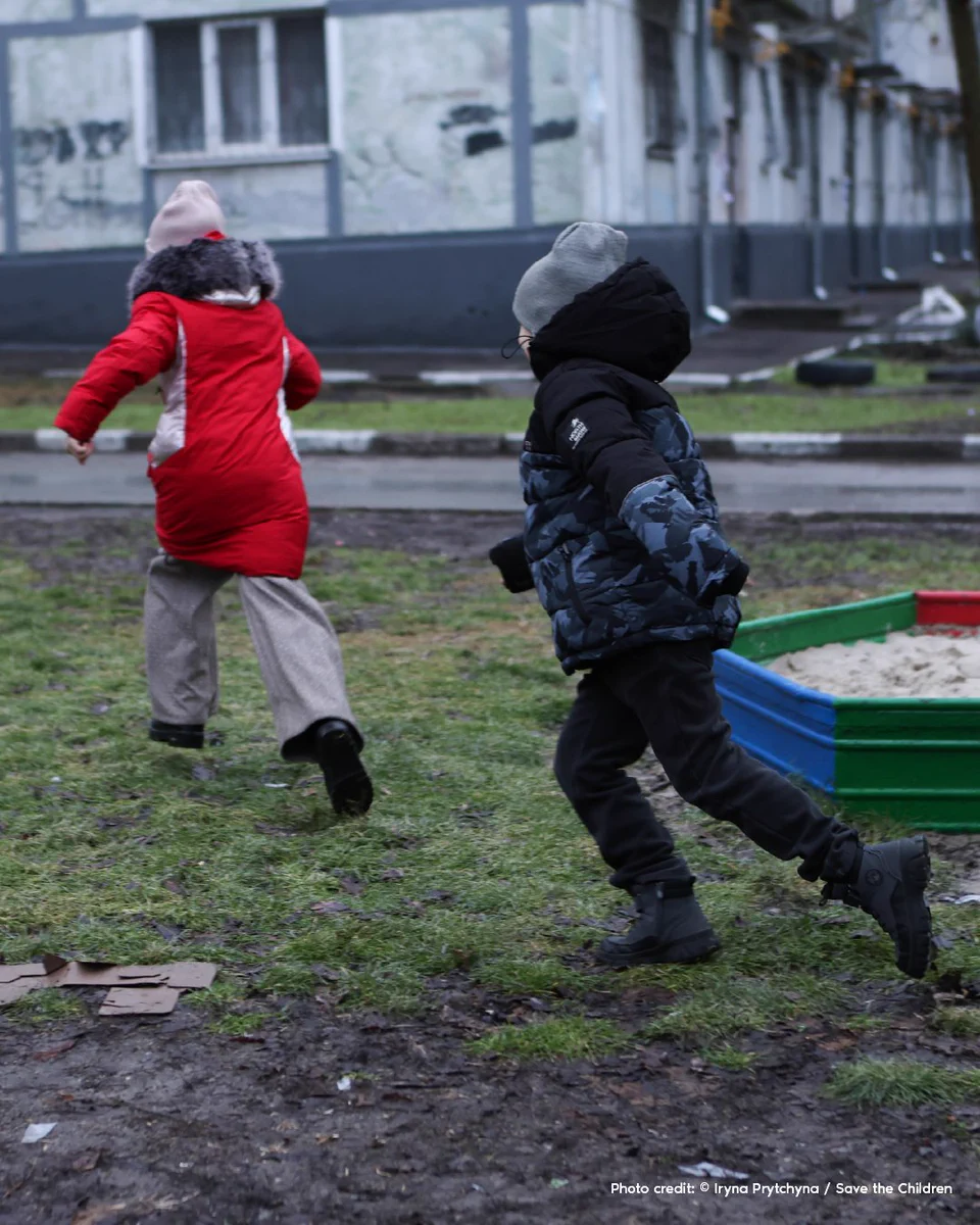 Two children in winter clothing play a game of chase in a small playground in Zaporizhzhia, Ukraine.