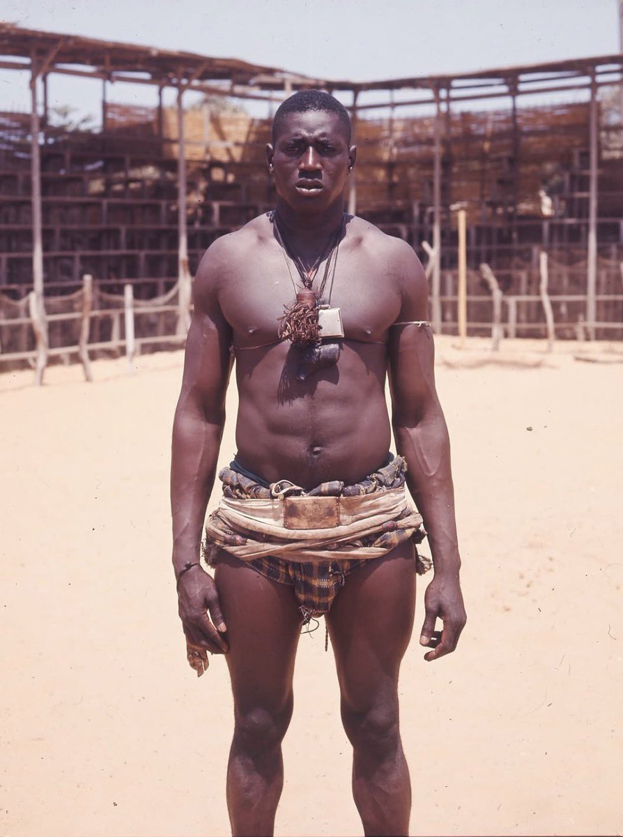 LutteTv's tweet photo. Mamadou Sakho, dit Double Less

Dans les terres de Malfara, au cœur de la Casamance, naquit un colosse dont les bras semblaient mesurés à l’aune de deux mètres de tissu. On l’appela Double Less. Les anciens disent que ses enjambées couvraient déjà l’arène avant même qu’il n’y mette le pied.
En 1972, encore inconnu, il affronte Doudou Baka Sarr. Le combat se termine par un nul. Le jeune géant ne l’oublie pas. Plus tard, il revient et le terrasse. Dès lors, les ténors tombent les uns après les autres : Ibou Senghor, Pape Kane, Toubabou Dior, Moussa Diamé, Mame Gorgui Ndiaye… Ses longs bras fermaient l’espace comme une porte de fer. Personne n’entrait dans sa garde sans en payer le prix.
Face au Tigre de Fass, Mbaye Guèye, il livra des duels qui restèrent gravés dans la mémoire du Sénégal. L’un d’eux n’eut jamais de verdict. Youssou Ndour en fit une chanson. Le peuple attendit le jugement jusqu’à la fin de leurs deux vies.
Double Less ne se contenta pas des arènes sénégalaises. Il porta les couleurs du pays à Montréal, Moscou et Los Angeles. Aux Jeux africains de Nairobi, il revint avec l’or. Il fut aussi champion de judo. On le surnomma le Seigneur des Arènes, non par flatterie, mais parce que l’arène elle-même semblait s’incliner devant lui.
Il forma deux fils qui héritèrent de sa stature et de sa fierté : Balla Gaye 2 et Sa Thiès. Il ouvrit une école à keur Massar pour que d’autres jeunes apprennent que la force sans dignité n’est rien.
Le 5 septembre 2021, le Seigneur des Arènes s’en alla. Il avait 77 ans. Le Sénégal pleura un père, un champion et une époque.
On raconte encore que, les soirs de grand combat, quand le vent soulève la poussière de l’arène, on entend le bruit sourd de ses pas. Double Less n’est plus là. Mais la légende, elle, n’a jamais quitté le cercle.